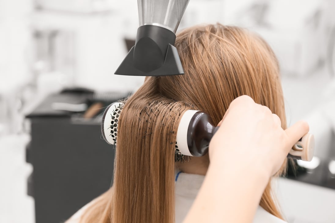 Female Hairdresser Blow Drying Hair of Client in Beauty Salon, Closeup